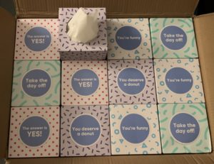 A box full of tissue boxes from Who Gives A Crap, each with different sayings on the removable tab.